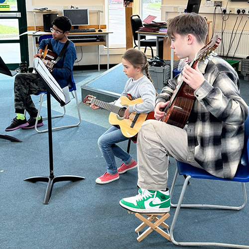 Three students playing guitar